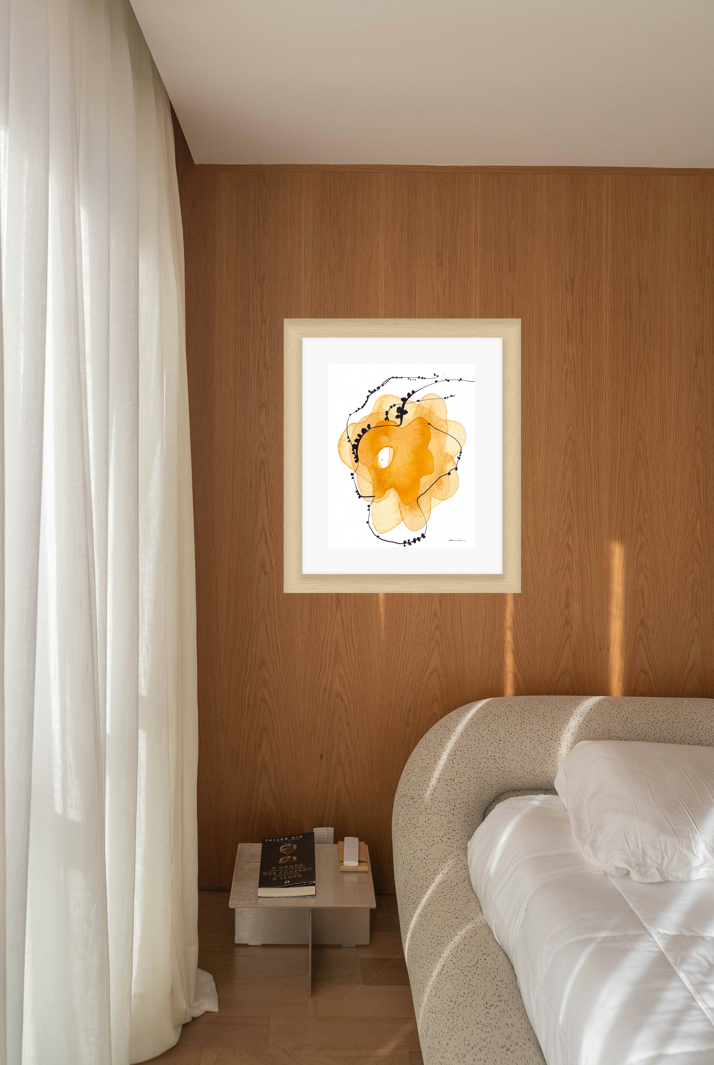 Framed abstract art piece on a wall above a bed in a bedroom.