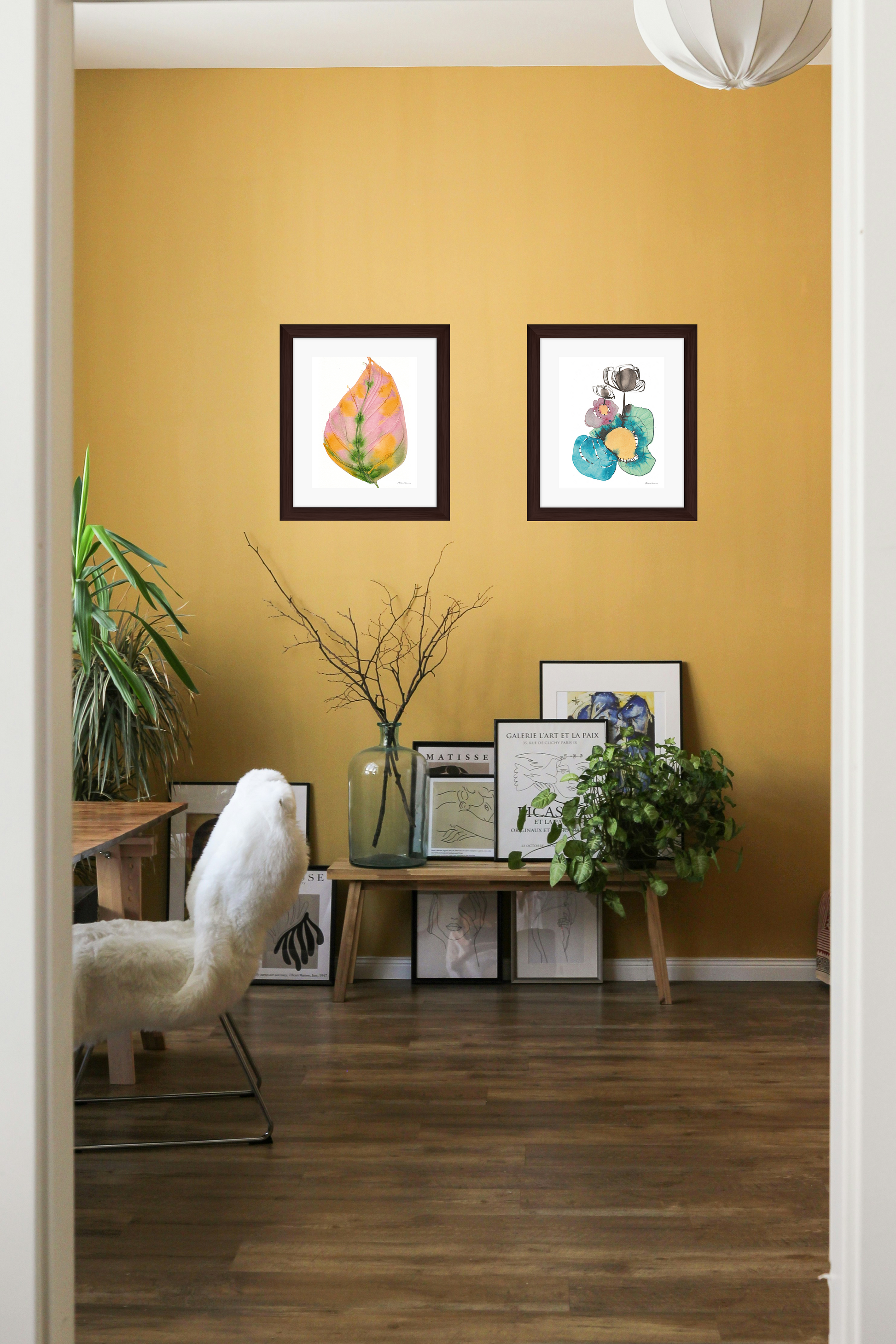 Living room with yellow walls, framed artwork, and a white armchair.