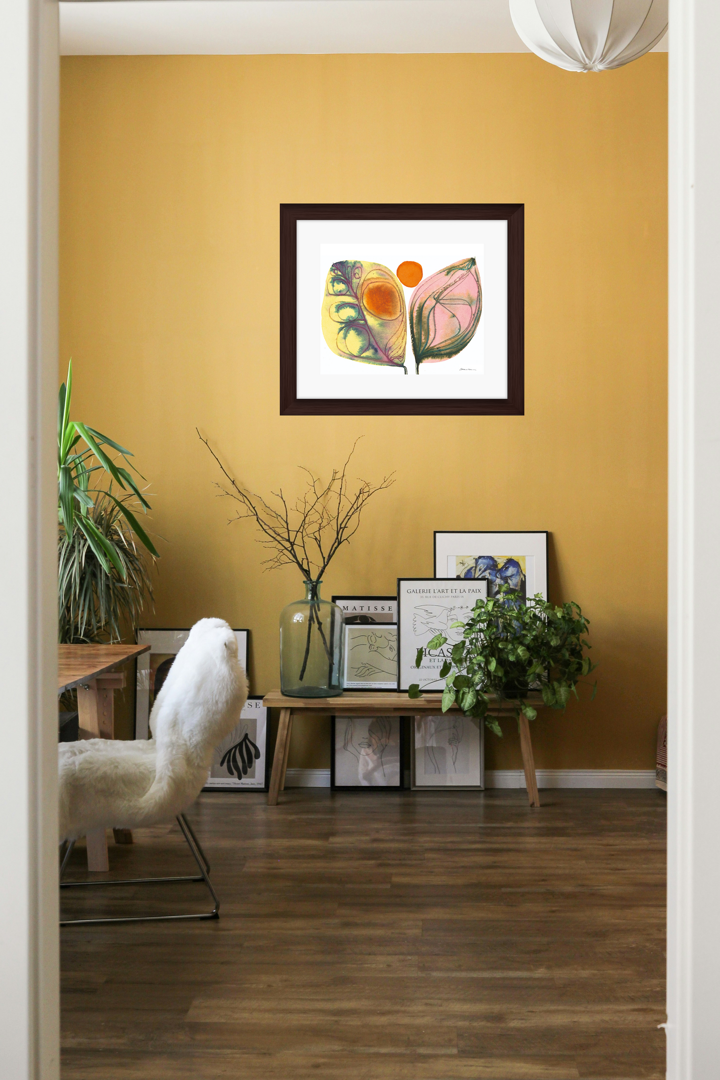Living room with a yellow wall, framed artwork, and decorative items.