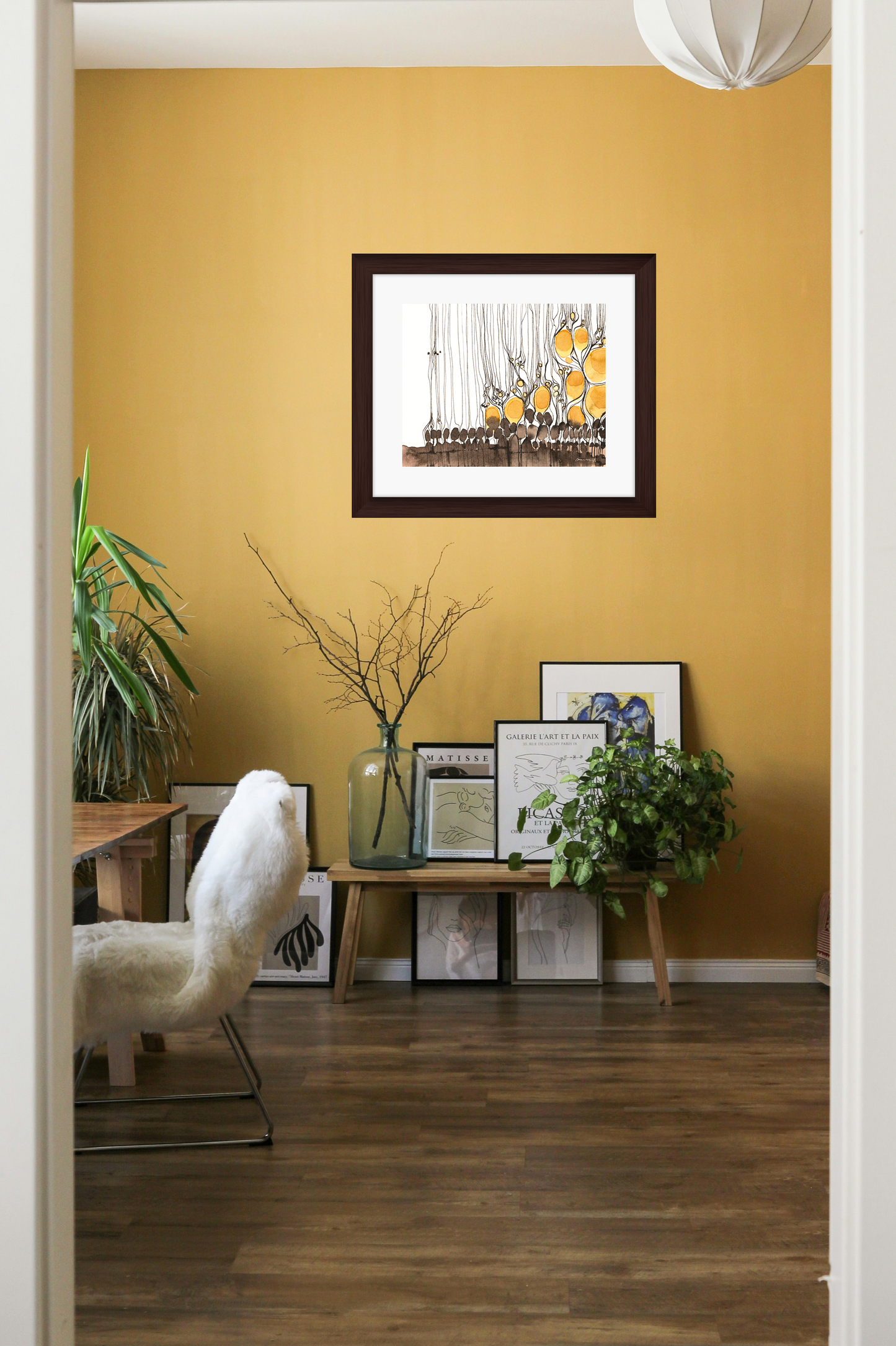 Living room with yellow walls, framed pictures, and a white armchair.